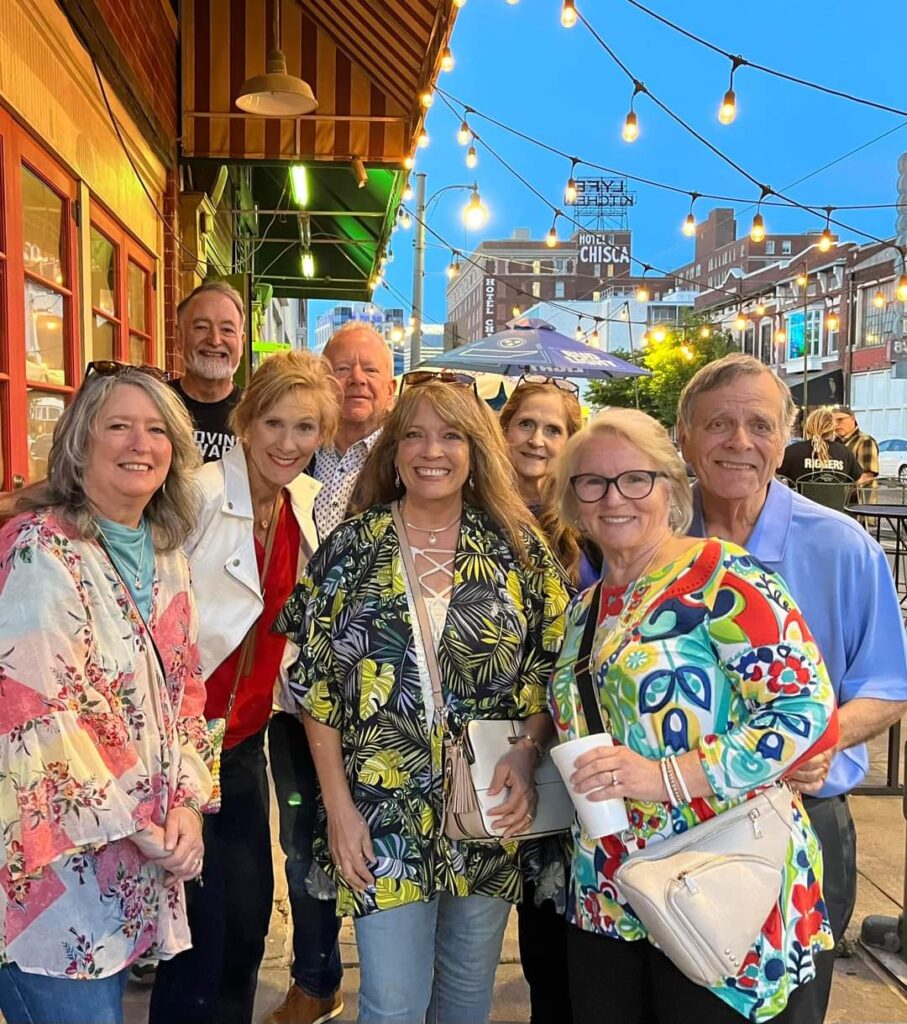 Eight people standing outside next to a building and smiling.