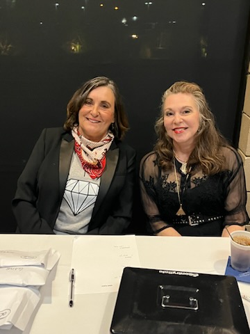 Two people sitting at a table and smiling.