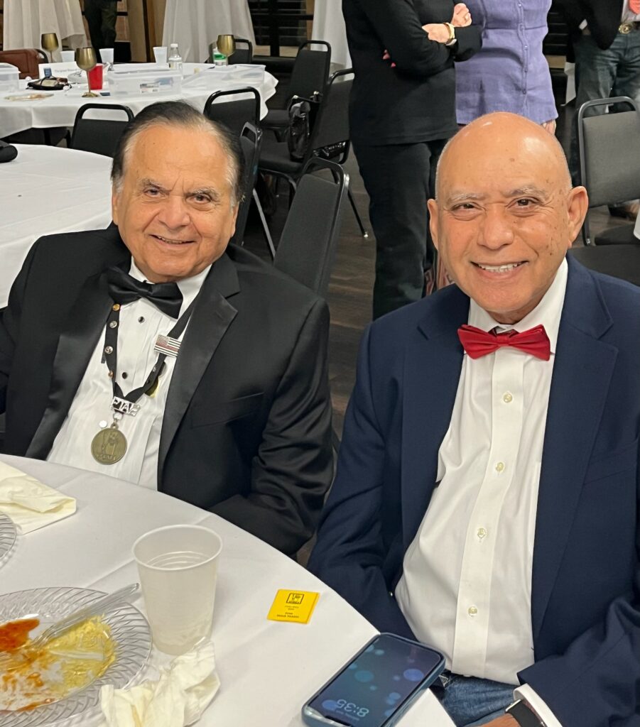 Two people sitting at a table and smiling.